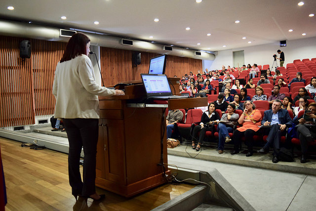Una profesora hace una presentación en un auditorio lleno
