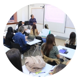 Docente dando clase a un grupo de estudiantes en un salón de clases.