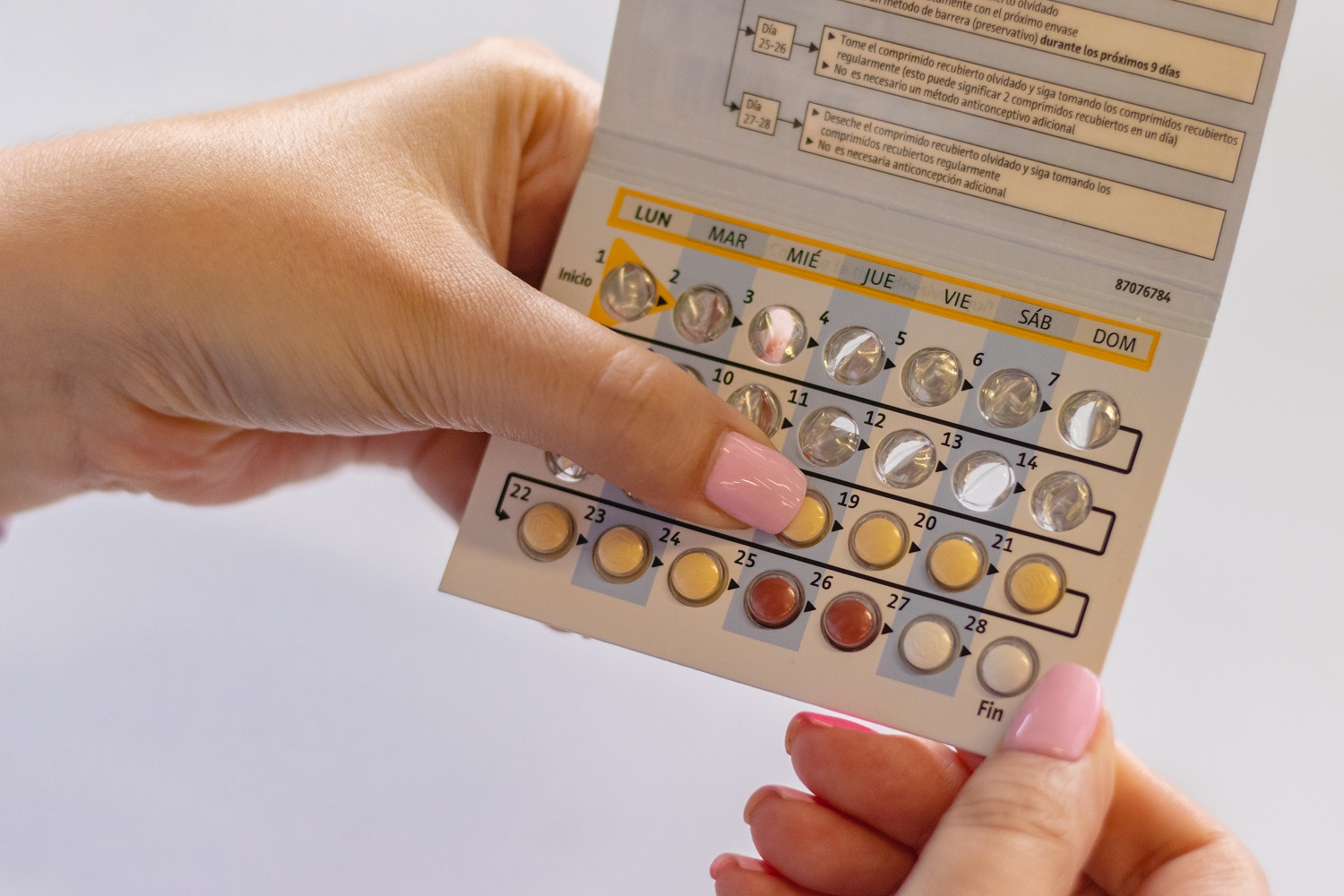 Mujer sosteniendo pastillas anticonceptivas